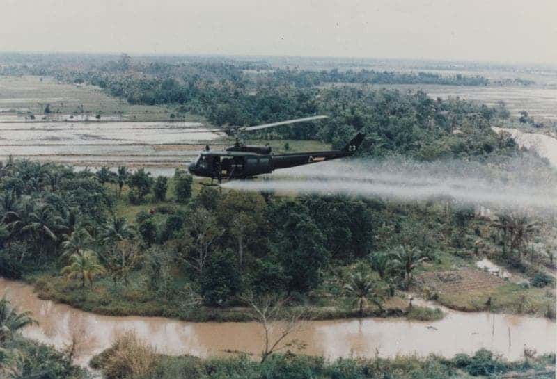 U.S. Army Huey helicopter spraying Agent Orange over Vietnamese agricultural land