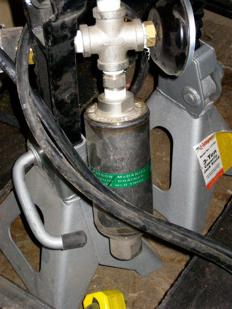 A sampling port is connected to the bottom of the white bucket that holds the yellow tubing (see previous picture), which collects the bio-oil and automatically empties it into a drip pan. Other re:char prototypes, like the Norfolk, Connecticut farm unit, use old water-cooler tanks to store the bio-oil.