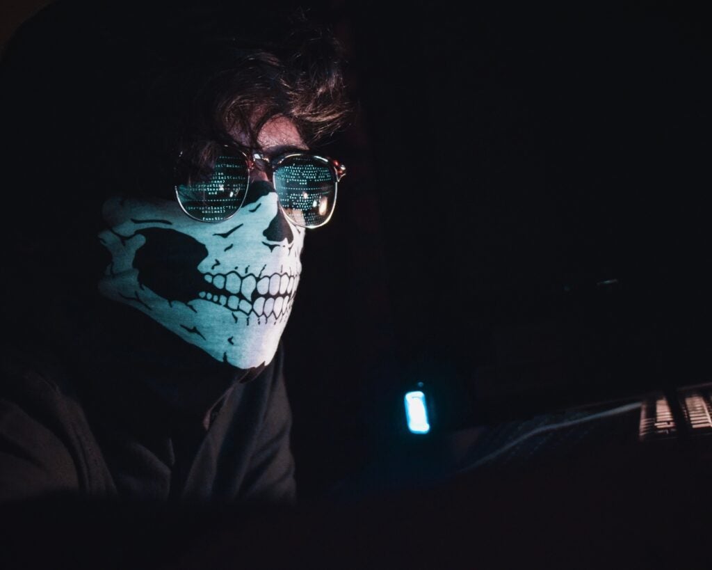 a person wearing a skull mask sitting in the dark