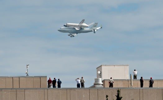 People stand on the roof of the Labor Department building to watch as the shuttle takes its final (assisted) flight.