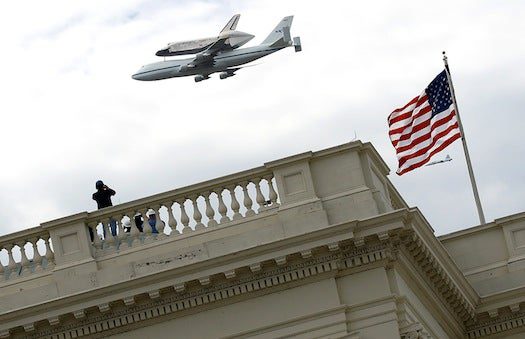 A closer shot of the shuttle zooming over the Capitol building.