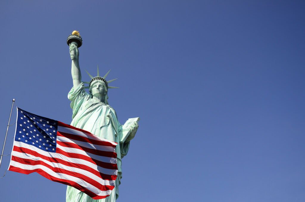 The Statue of Liberty with an American flag flying in front