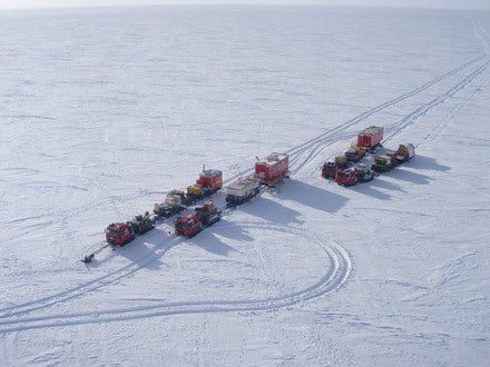 The traverse vehicles sit in caravan style near the inactive Plateau Station on the central Antarctic Plateau.