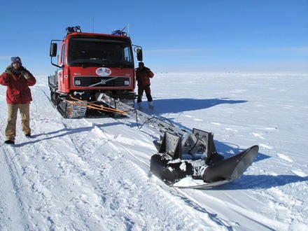 The expedition equipment includes a laser that detects crevasses—deep vertical cracks in the ice that pose potential danger to the expedition. This image shows two team members examining the laser attached to one of the vehicles.