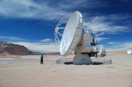 A paramedic stands next to one of ALMA's 12-meter radio antennas. The Array Operations Site is at such a high elevation that many people experience altitude sickness; paramedics are always on site to provide extra oxygen.