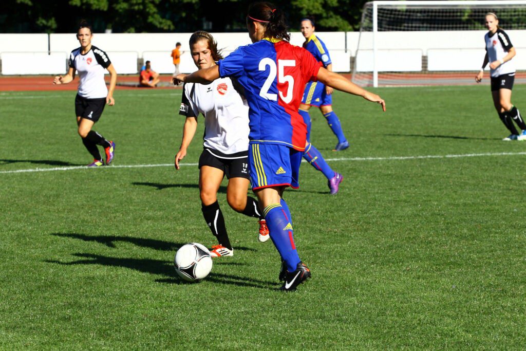 women playing soccer on turf field