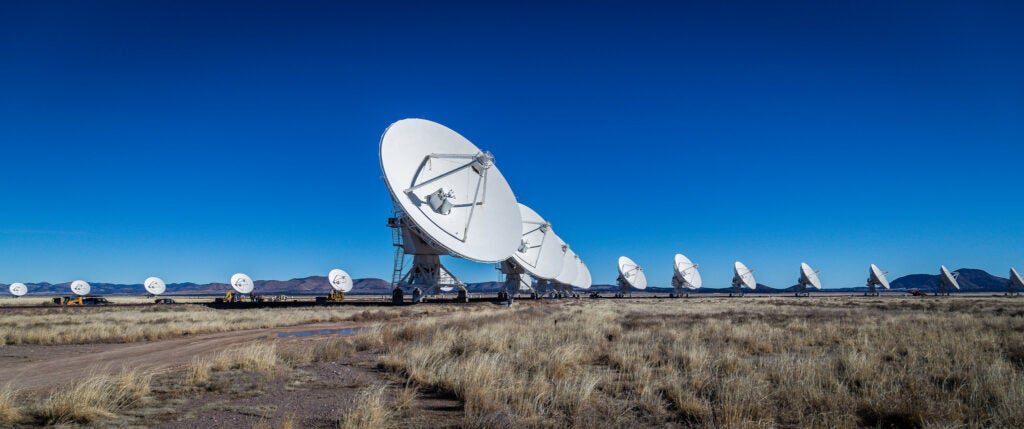 A line of satellite dishes pointed towards a blue sky