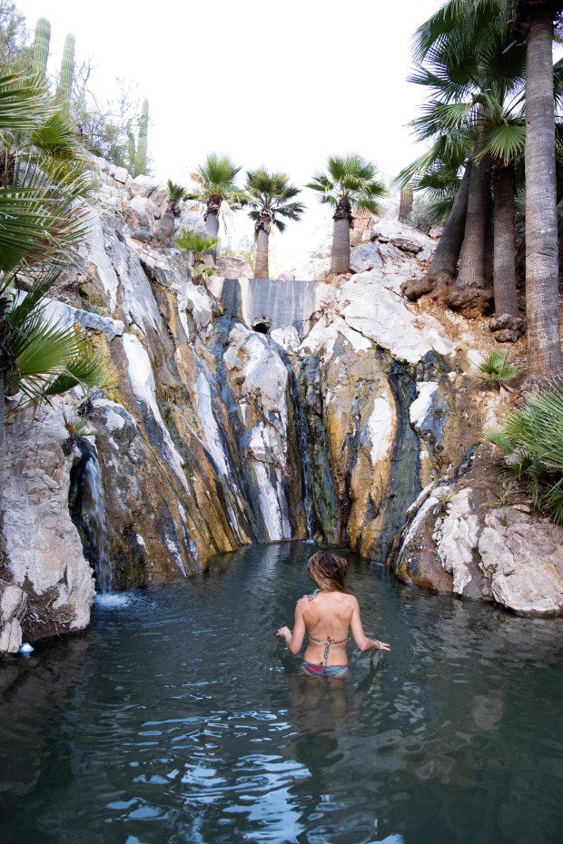 A woman stands in hot springs.