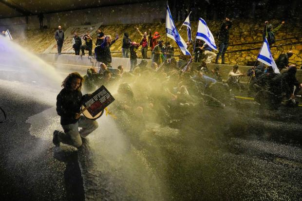 Police use a water cannon to disperse demonstrators protesting against Israeli Prime Minister Benjamin Netanyahu's government, and calling for the release of hostages held in the Gaza Strip by Hamas group, in Tel Aviv, Israel, Saturday, March 9, 2024. With each passing day, the relatives of hostages in Gaza face a deepening despair. (AP Photo/Ariel Schalit)