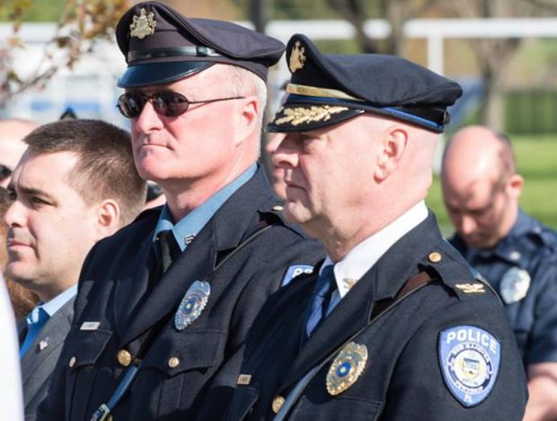 2 police officers in uniform standing outdoors looking ahead