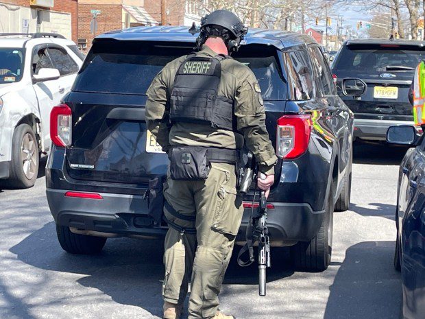 An armed law enforcement officer stands at ready Saturday, March 16, 2024, on Martin Luther King Boulevard in Trenton. Andre Gordon Jr., the suspect in two shootings in Bucks County that left 3 people dead, was barricaded inside a home and holding hostages, authorities said. (L.A. Parker/The Trentonian)