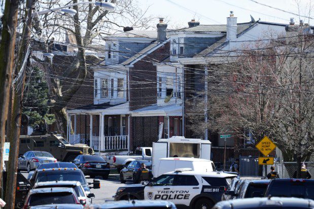 Police surround a home in Trenton, N.J., on Saturday, March 16, 2024. A suspect has barricaded himself in the home and was holding hostages after shooting three people to death in suburban Philadelphia. (Matt Rourke/AP)