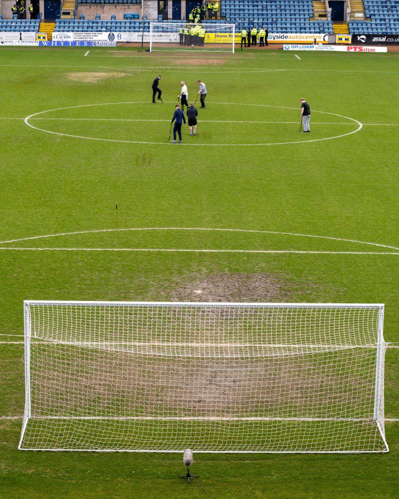 Staff work on the waterlogged pitch.