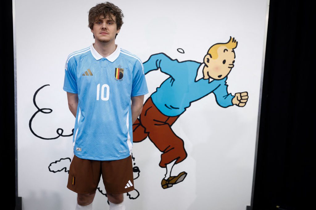 A model poses in Belgium's away kit for Euro 2024  in front of a picture of Tintin