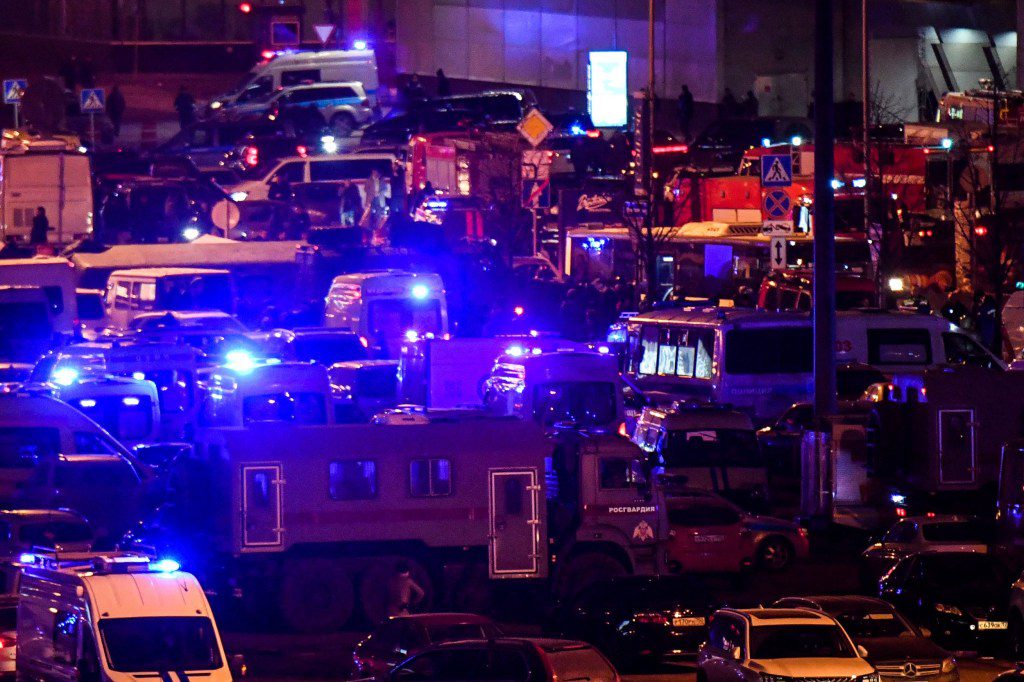 Emergency services personnel and law enforcement officers are seen outside the Crocus City Hall 