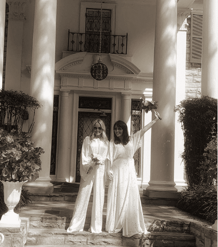 Kate Brooks and Michelle Hardwick on the stairs of a grand building on their wedding day