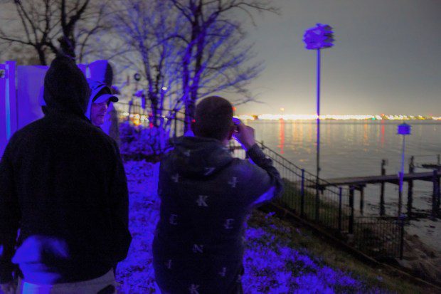 Concerned visitors wait for their turn to peer through binoculars toward the Francis Scott Key Bridge which lies in ruins in the waters of the Patapsco River after a container ship collided with the structure overnight. (Karl Merton Ferron/Staff)