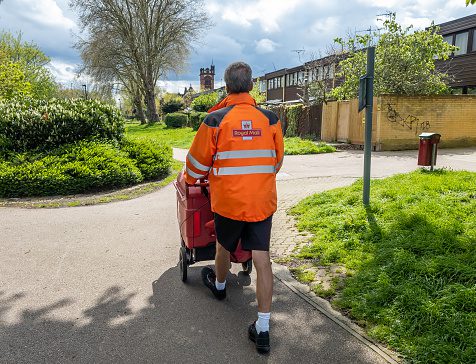 A Royal Mail postman doing his rounds on house to house postal delivery.