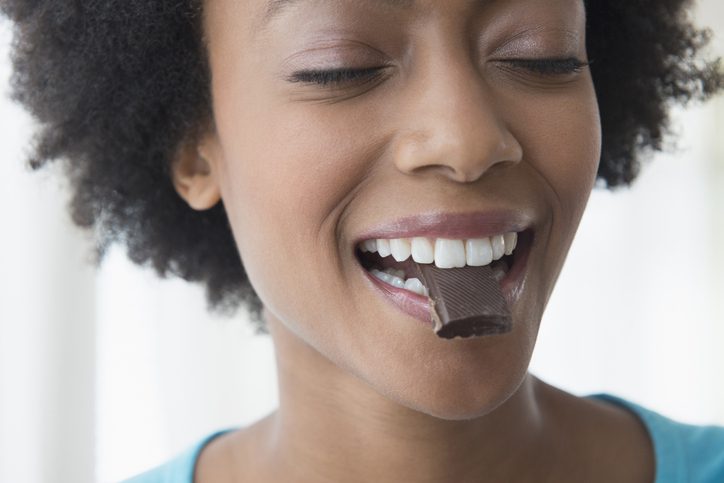 Close up of African American woman eating square of chocolate