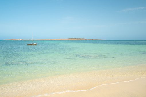 A small boat bobs around on the clear waters of Boa Vista, 