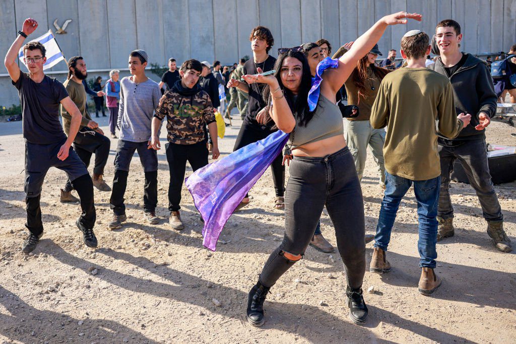 People dance as right-wing Israeli protesters gather to block the entry of humanitarian aid trucks to the Gaza Strip, on the Israeli side of the Kerem Shalom border crossing with the Palestinian territory on February 6, 2024 amid the ongoing conflict between Israel and the Palestinian militant group Hamas. (Photo by Menahem Kahana / AFP) (Photo by MENAHEM KAHANA/AFP via Getty Images)