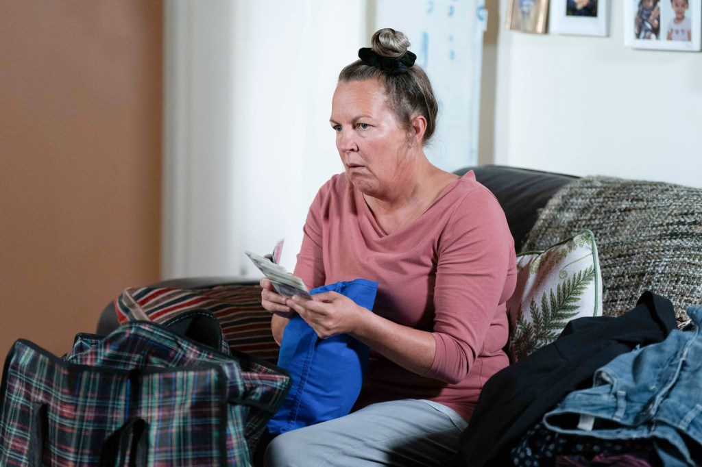 Karen holds a wad of cash in EastEnders