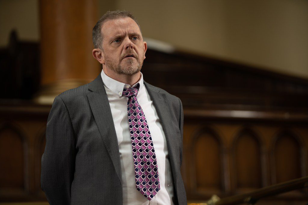 Dan is dressed in a suit and tie as he awaits his verdict in court in Emmerdale