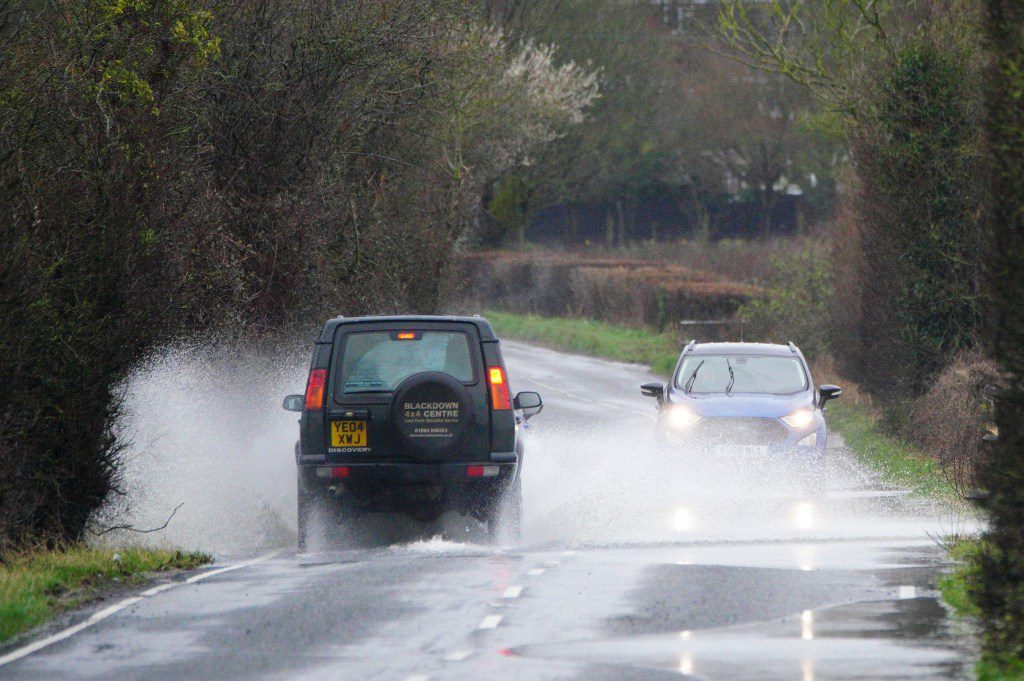 Vehicles are driven through water collected on a roadway in the Somerset Levels in Somerset. 