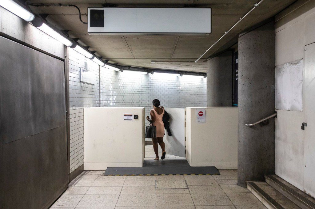 A person walking through a white barrier fence with no signs.