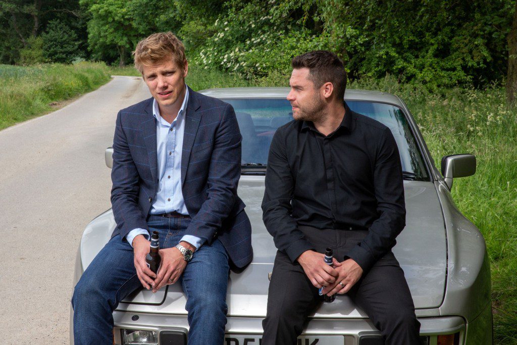 Robert and Aaron sitting on the hood of a car in Emmerdale