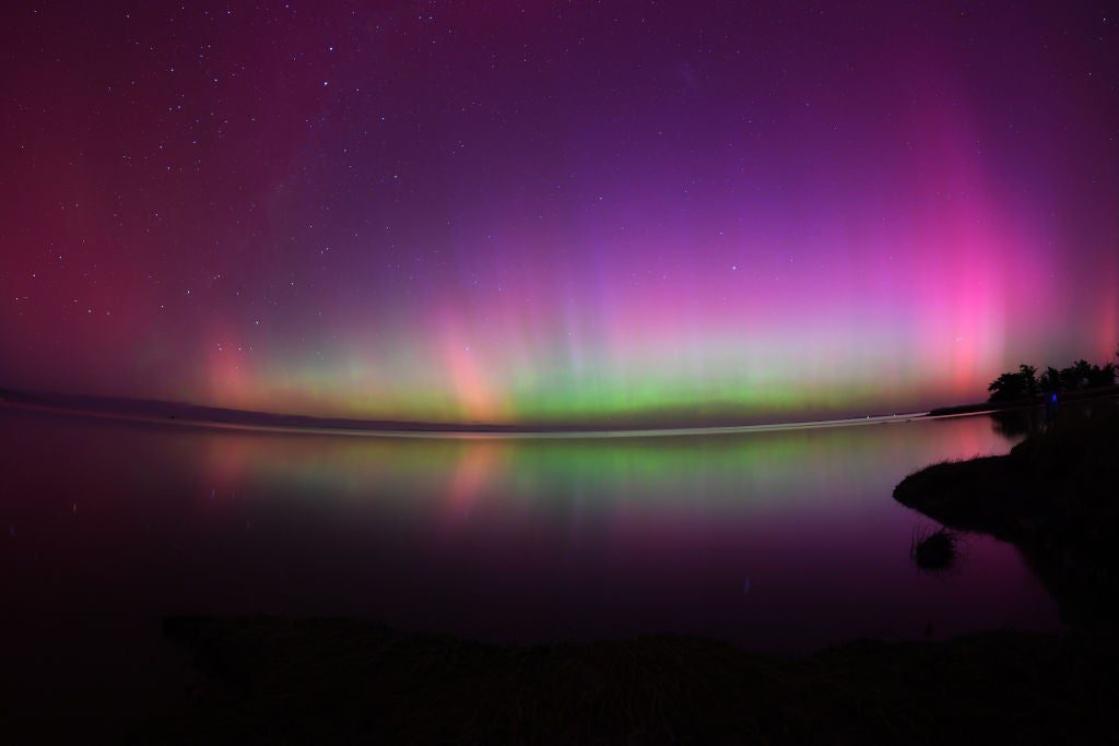 The Aurora Australis, also known as the Southern Lights, glow on the horizon over waters of Lake Ellesmere on the outskirts of Christchurch on May 11, 2024. The most powerful solar storm in more than two decades struck Earth, triggering spectacular celestial light shows from Tasmania to Britain -- and threatening possible disruptions to satellites and power grids as it persists into the weekend. (Photo by Sanka Vidanagama / AFP) (Photo by SANKA VIDANAGAMA/AFP via Getty Images)